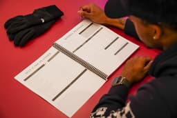 Student sitting at table reading planner with Self Care Planner and Weekly Planner pages shown.