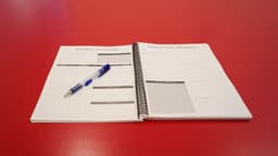 Planner sitting on table with Weekly Planner and Gratitude journal pages shown.